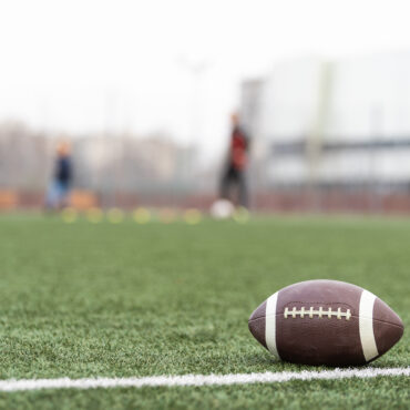Football on football field with players in background