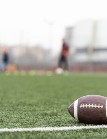 Football on football field with players in background