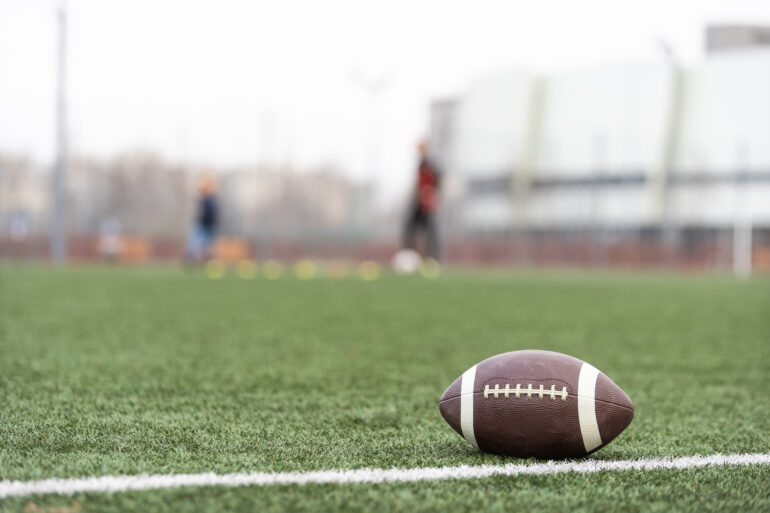 Football on football field with players in background